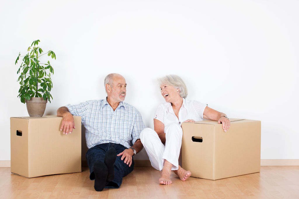 2 senior citizens sitting next to boxes